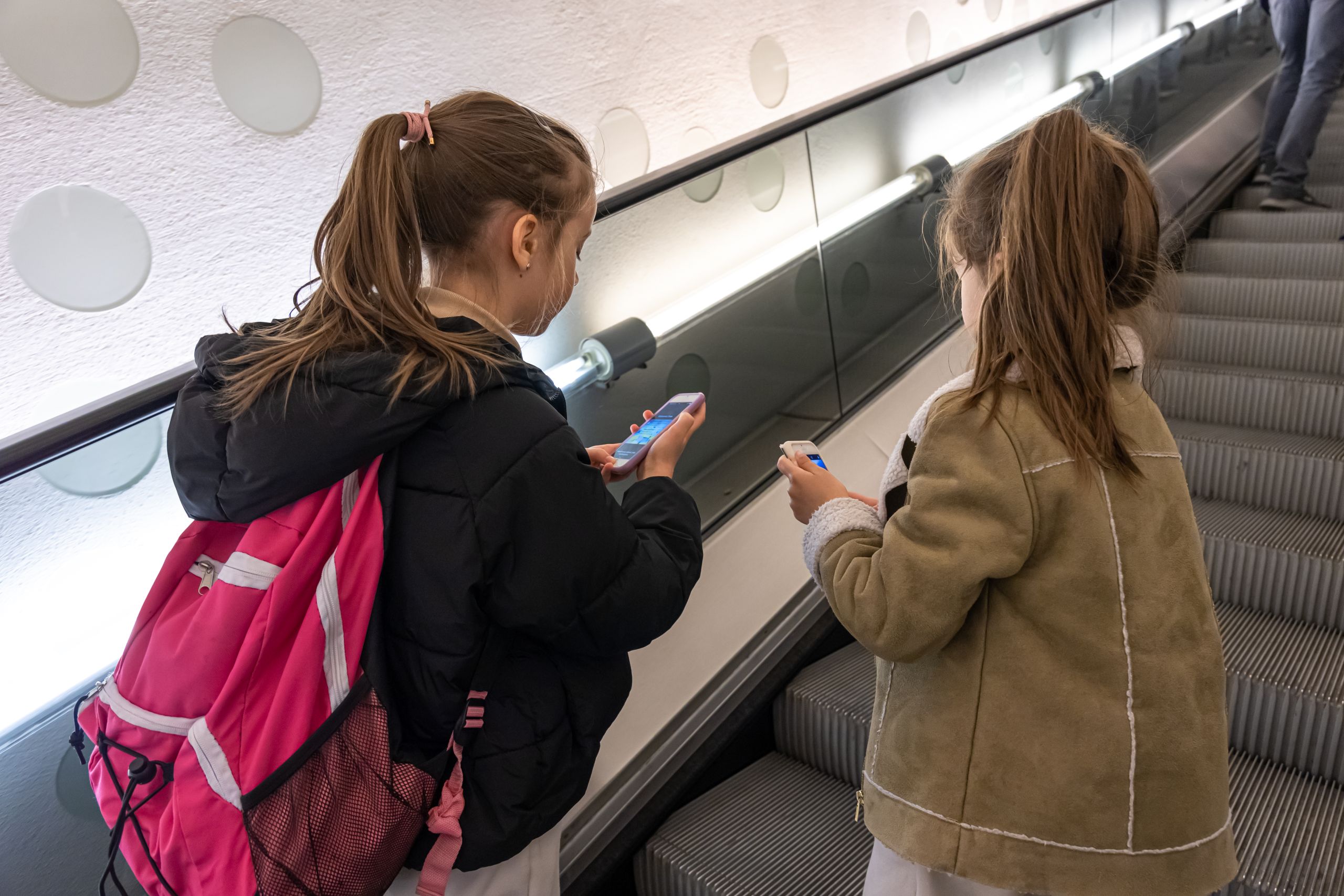 Little girls with smartphones on the excavator. Students met at the airport